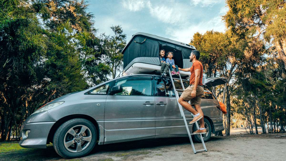 Spaceships campervan with rooftop tent: kids in the rooftop tent while dad is standing on the ladder