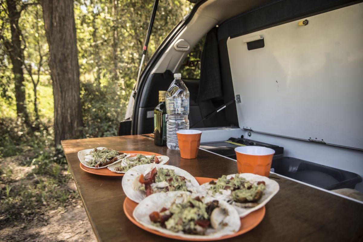 Two plates of freshly made tacos are sitting side-by-side on the cooking area of a Spaceships campervan